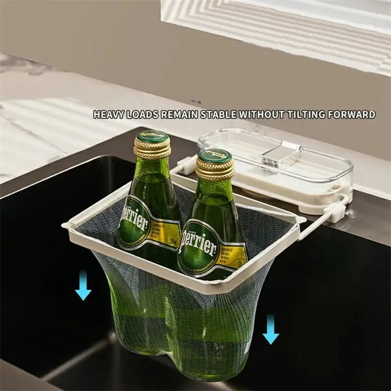 White mesh kitchen sink filter rack with clear plastic lid and mesh strainer bags holding two green Perrier bottles.