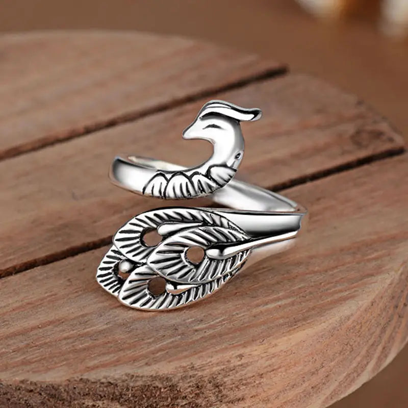 Adjustable silver peacock and fish crochet tension ring featuring intricate feather detailing and a sleek band.