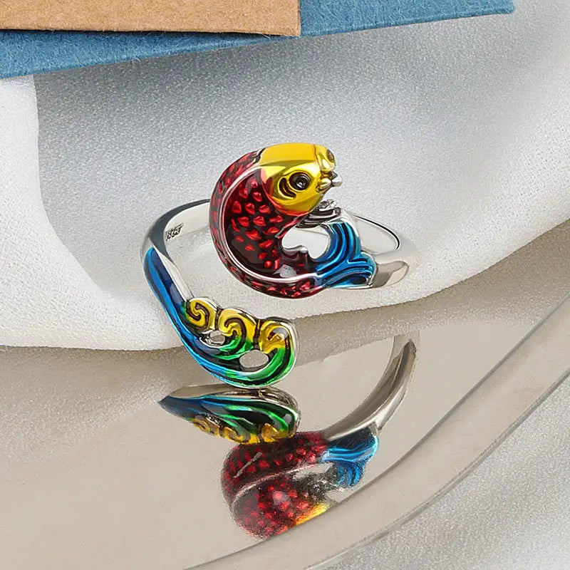 A vibrant silver adjustable fish ring with colorful red yellow blue and green enamel detailing from the peacock and fish crochet tension rings collection.
