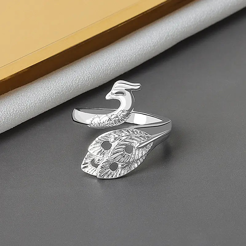 Silver peacock-themed adjustable ring with intricate feather detailing and polished metallic finish from adjustable peacock and fish crochet tension rings collection.