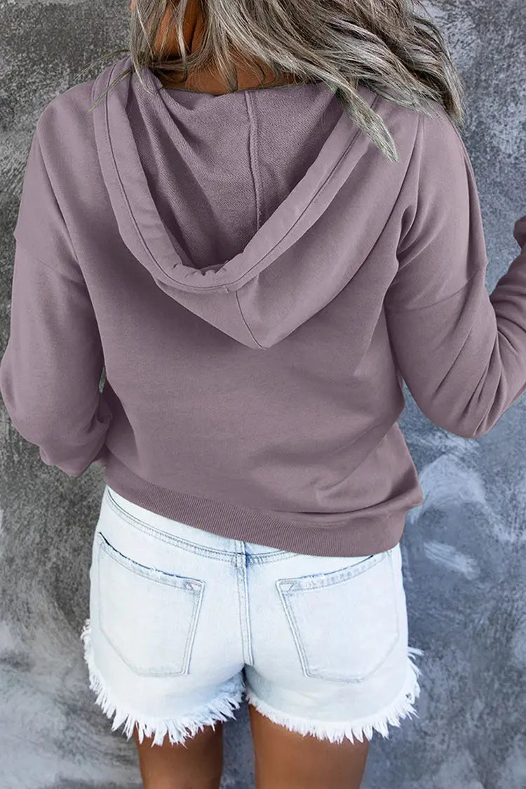 A soft mauve-colored women’s button neck drawstring hooded sweatshirt with a relaxed fit long sleeves and ribbed cuffs.