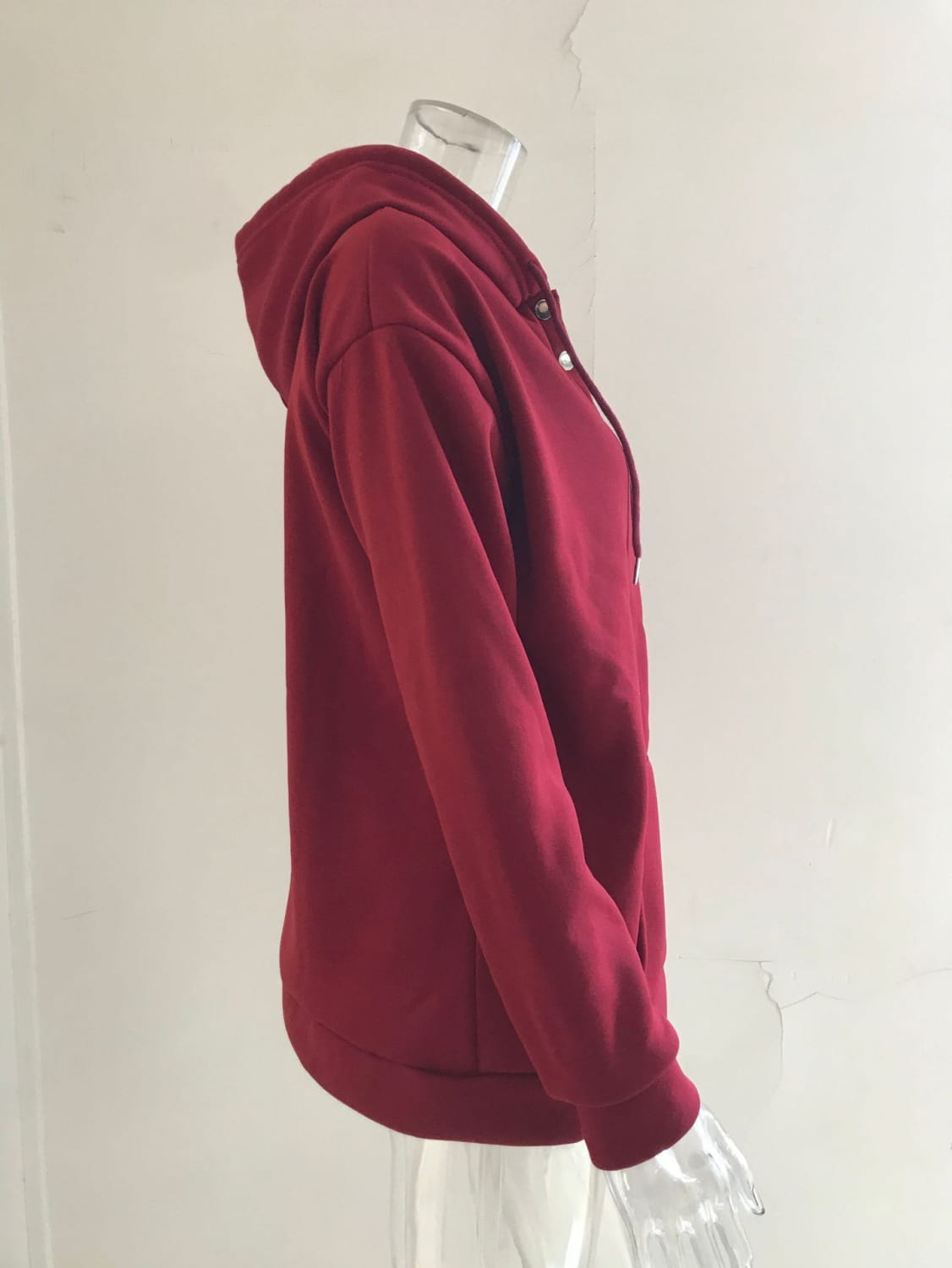 A rich maroon women’s button neck drawstring hooded sweatshirt made of soft cotton fabric with a front zipper and button closure.