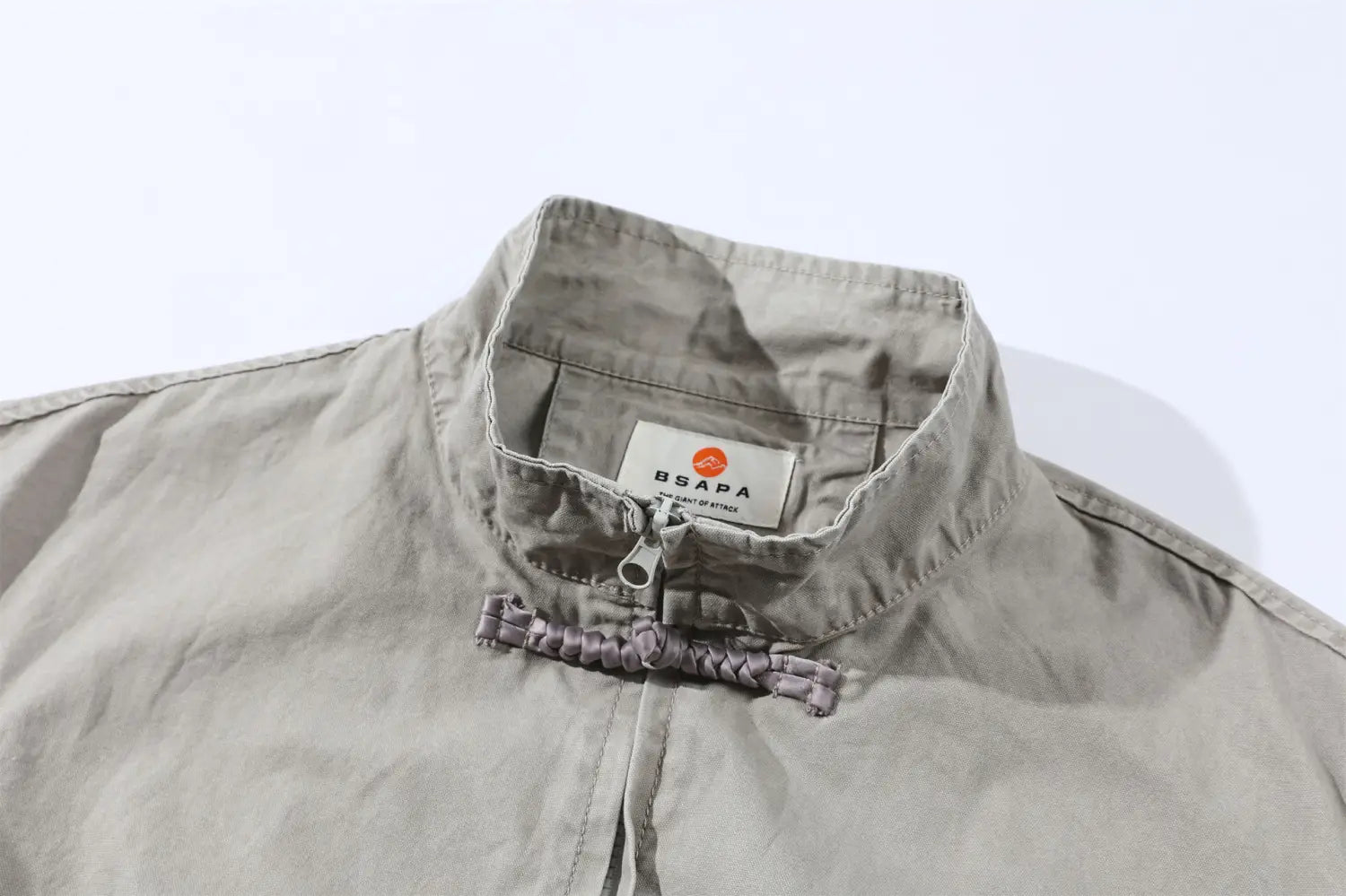 Une veste rétro pour homme de style chinois en beige, avec une fermeture à cordon tressé et un design minimaliste subtil.