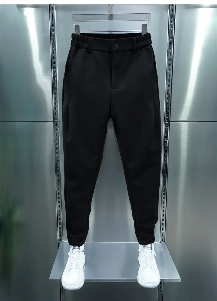 Men’s casual tapered jogger pants in black with elastic waistband and side pockets displayed on a hanger against metallic shelving.