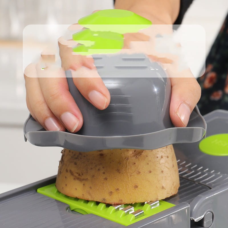 Gray and green vegetable chopper 13 in 1 mandoline slicer with blades slicing a potato for efficient vegetable preparation.