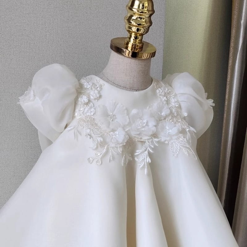Robe de mariée princesse en dentelle florale blanche pour filles, réalisée dans un satin blanc délicat, avec des manches bouffantes et des appliqués complexes en dentelle florale ornant l’encolure.