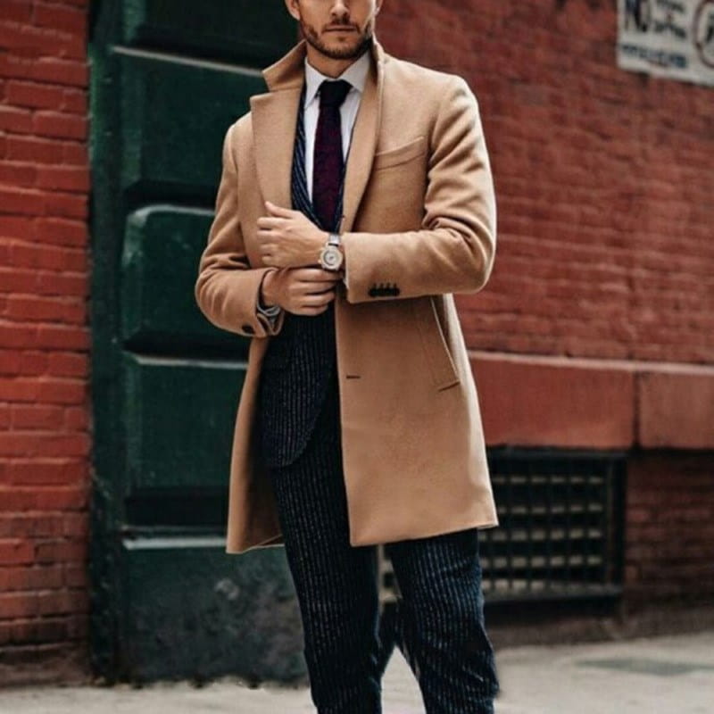 A man wearing a camel-colored mens double sided woolen overcoat with notched lapels and two front pockets.