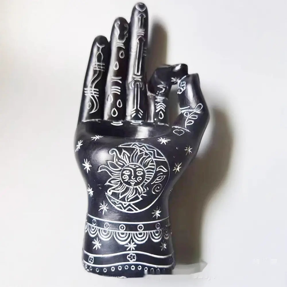 Black hand-shaped ceramic hamsa hand incense burner and candle holder figurine with intricate white etched sun and moon designs on the palm.