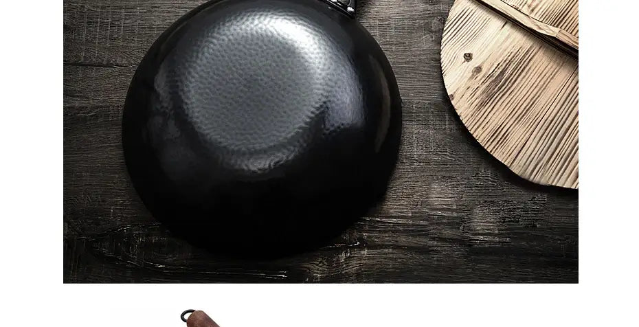 Wok artesanal de hierro hecho a mano de acero negro estampado a martillo con asa de madera, mostrado desde el frente sin la tapa de vidrio.