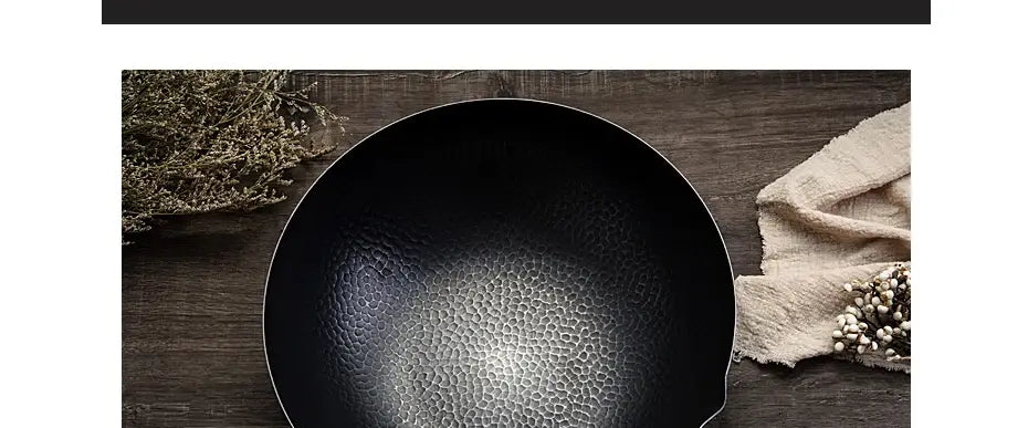 Wok de hierro hecho a mano en acero negro estampado a martillo con borde liso y redondeado y bordes ligeramente elevados, que incluye asa de madera y tapa de vidrio.