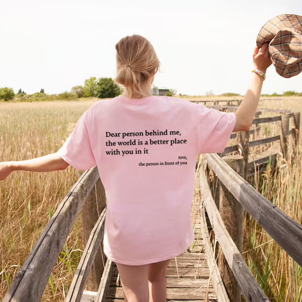 women’s oversized slogan print graphic t-shirt in pink featuring black printed text on the back side.