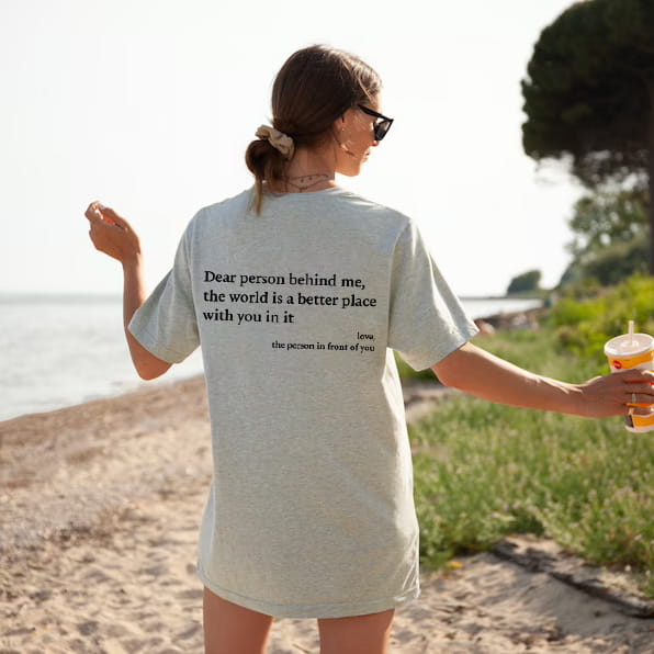Light gray oversized women’s t-shirt made of soft cotton featuring a black printed slogan on the back.