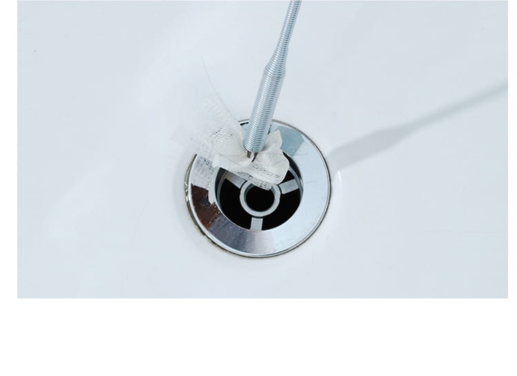 chrom chrome-finished bathtub drain with a flexible metal spring pipe clog remover tool inserted in the center