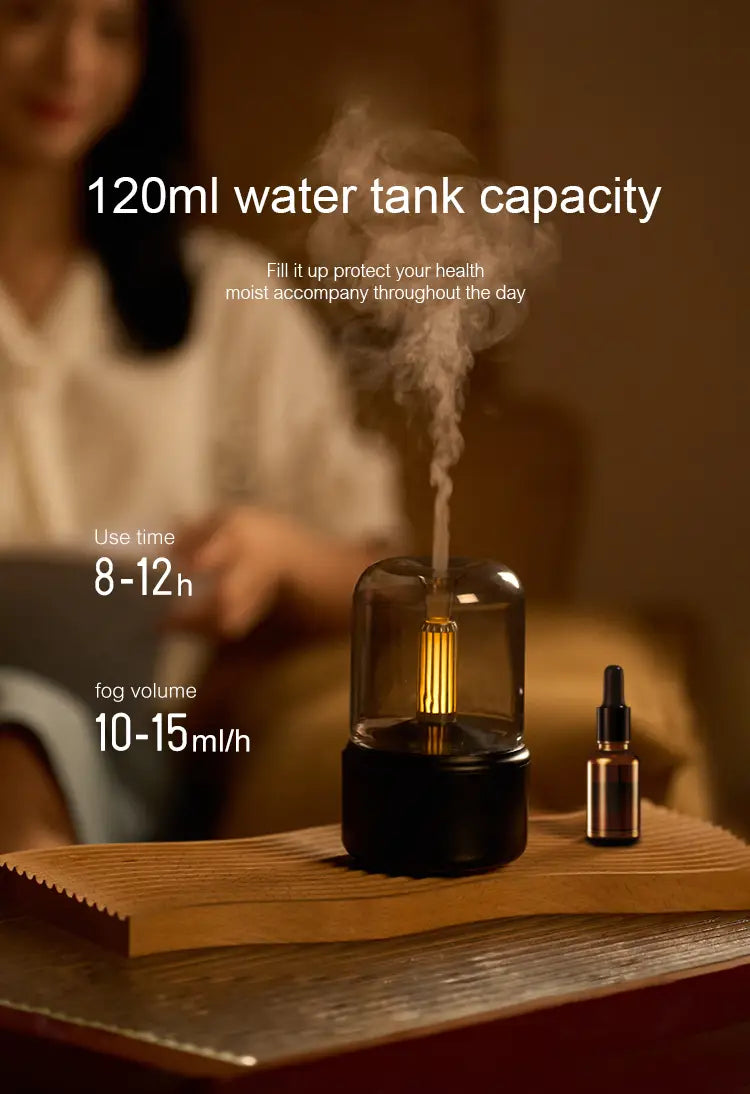 Black cylindrical usb mist humidifier with clear glass top and glowing internal led light next to a small amber essential oil bottle for candlelight aroma diffuser use 120ml capacity.