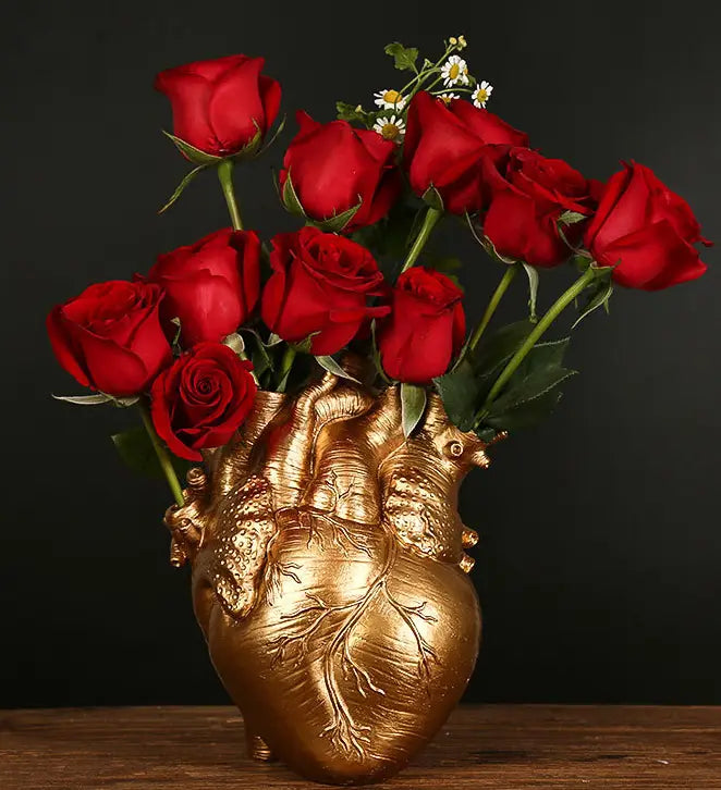 Golden anatomical heart vase made of Nordic resin sculpture filled with vibrant red roses and delicate white daisies as a decorative flower pot.