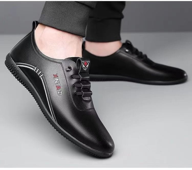 Zapatillas casuales planas con cordones de cuero negro para hombre, con logotipado plateado y detalle de logotipo rojo, suelas planas ligeras y transpirables.