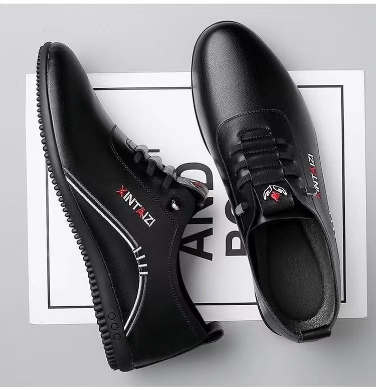 Zapatillas planas casuales de cuero negro para hombre con costuras blancas y un logotipo rojo sutil; son ligeras y transpirables.