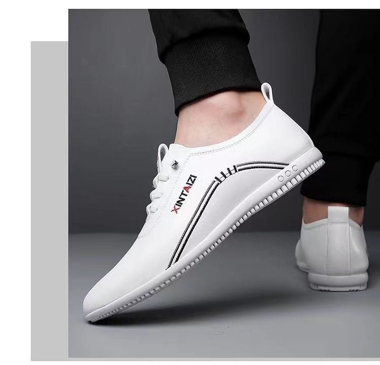 Zapatilla plana casual de cuero blanco con costuras negras y un logotipo sutil, diseñada para ser ligera y transpirable.