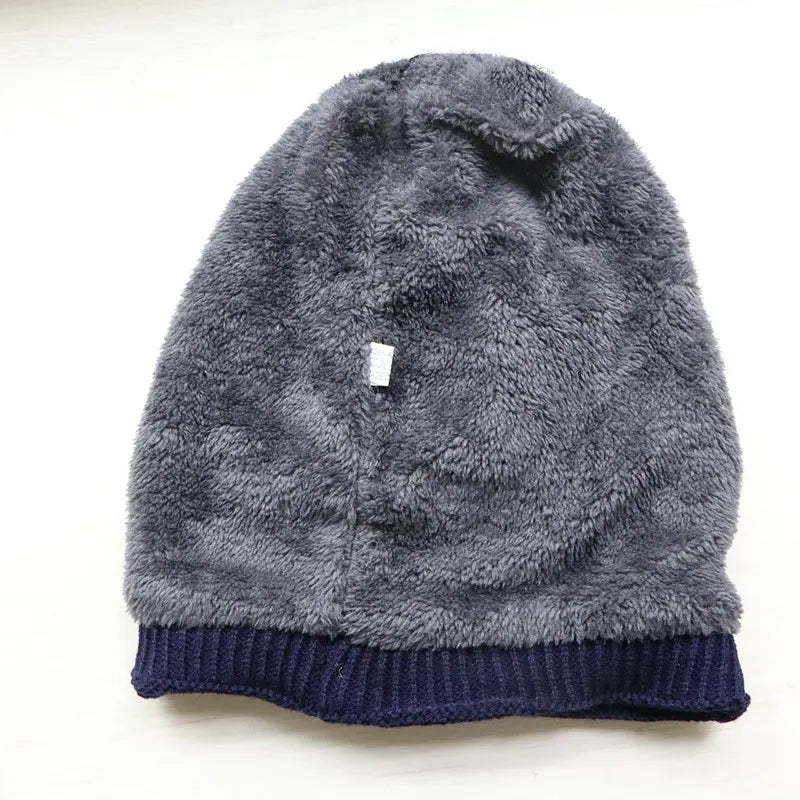 A cozy gray fleece lined knitted winter beanie hat featuring a ribbed navy blue cuff for men.