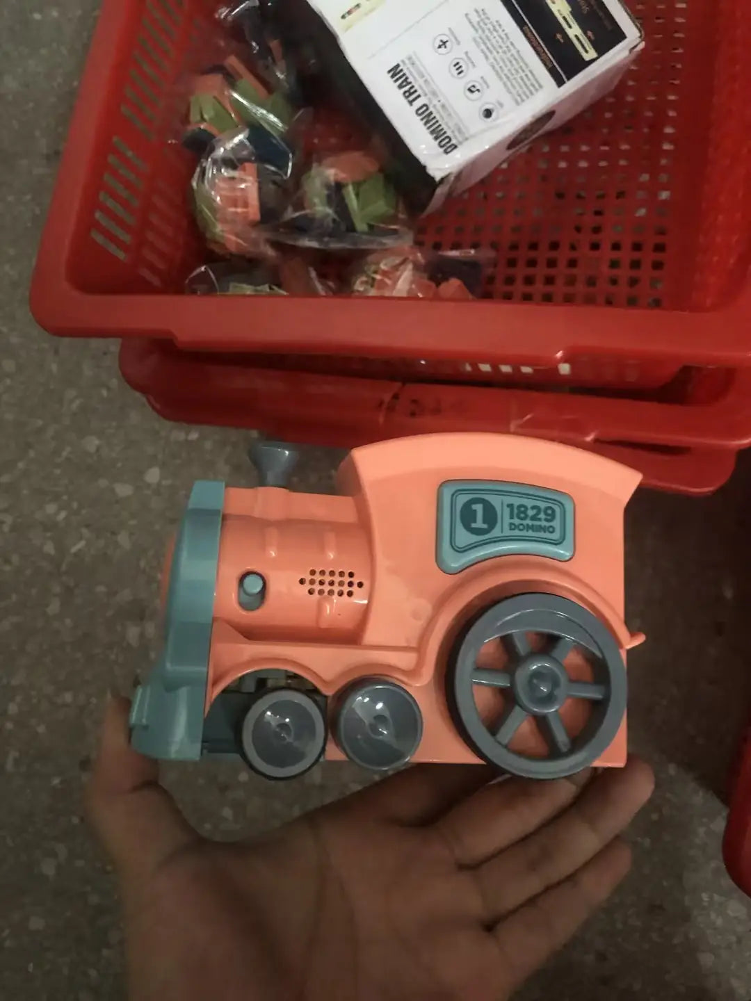 Orange and teal plastic domino train toy engine with gray wheels labeled 1829 domino for the automatic electric building blocks set.