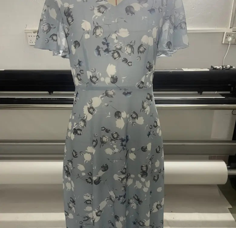 Une robe longue d’été à décolleté en V volanté, imprimé floral bleu clair, avec des manches courtes volantées.