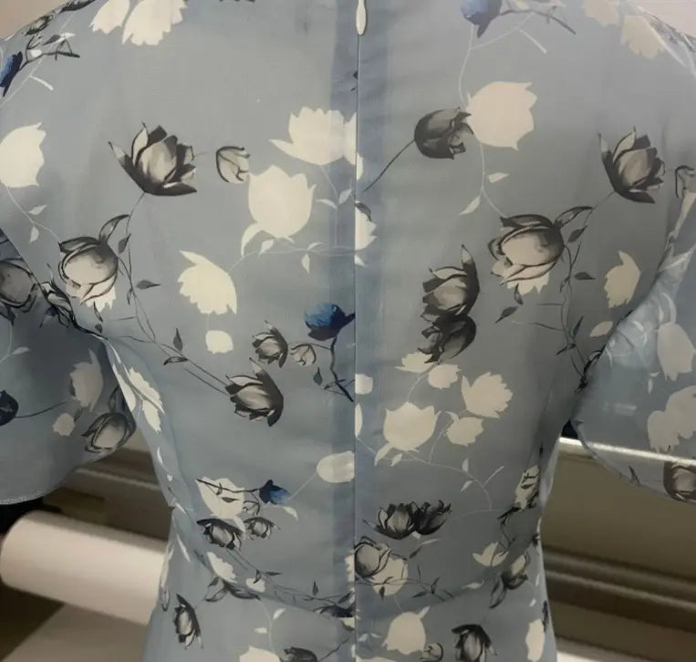 Une robe longue d’été à décolleté en V floral volanté bleu clair, présentant un motif floral délicat noir, blanc et bleu marine