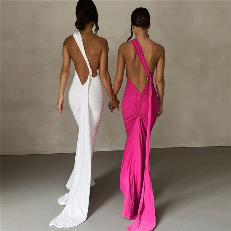 Two women wear elegant one shoulder mermaid backless train dresses in white and vibrant pink showing the back side of the form-fitting evening gowns.