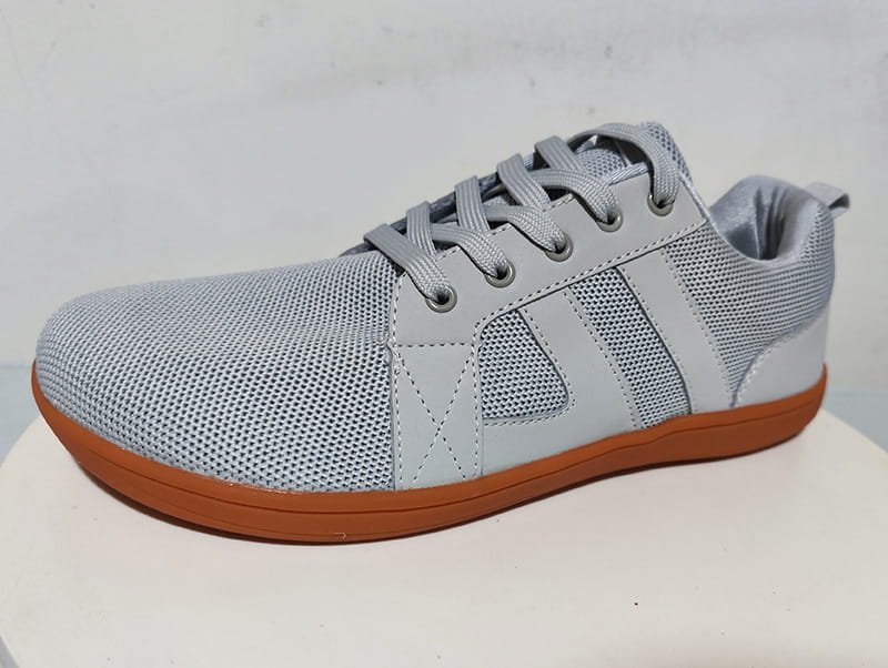 Gray mesh fly-knit wide last sneaker with breathable material, tan rubber sole, and matching gray laces.
