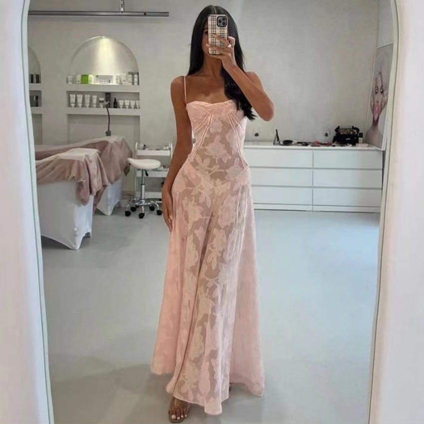 Une robe de soirée maxi en dentelle rose pâle, fluide, avec un corsage ajusté et un délicat motif floral.