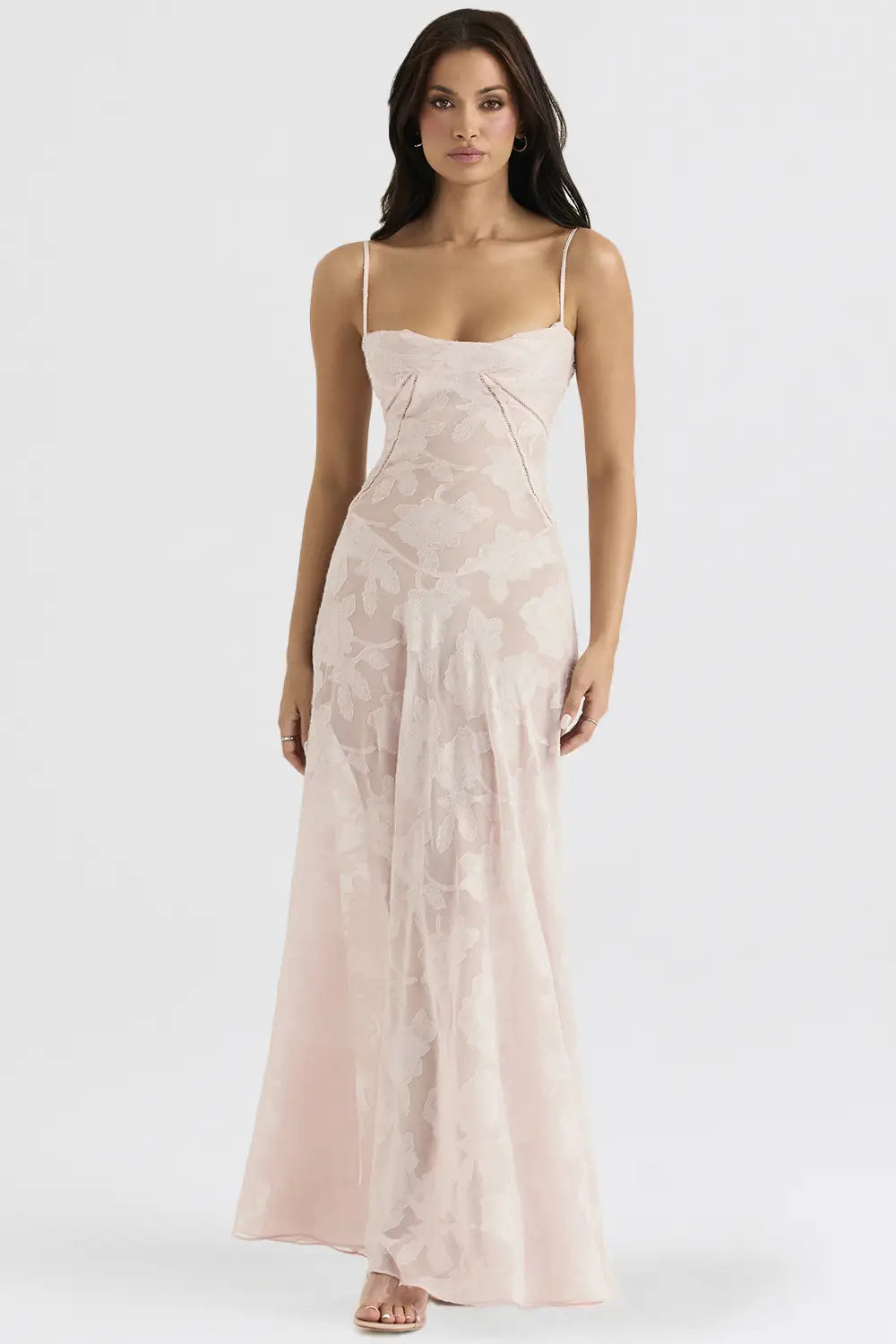 Une robe de soirée maxi sans dos en dentelle florale satinée rose blush, fluide, avec une délicate broderie florale et de fines bretelles spaghetti.