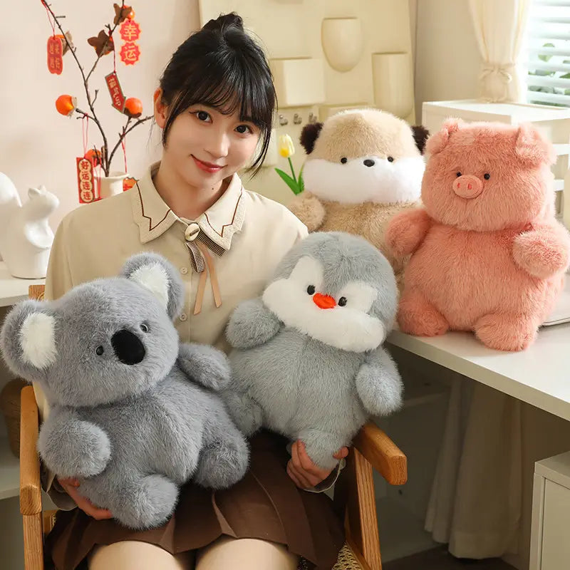 白い内側の耳と黒い鼻を備え、平らに寝かせたグレーのコアラのぬいぐるみで、もっちりした動物のぬいぐるみとしてデザインされた、やわらかな詰め物人形。