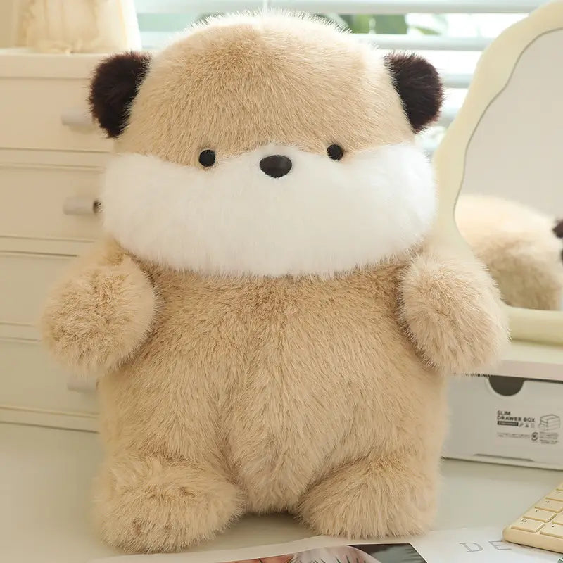 平らに寝かせた、もっちりした動物のぬいぐるみで、黒い耳と白い口先を備えた、やわらかなベージュのふわふわしたカワウソのデザイン。