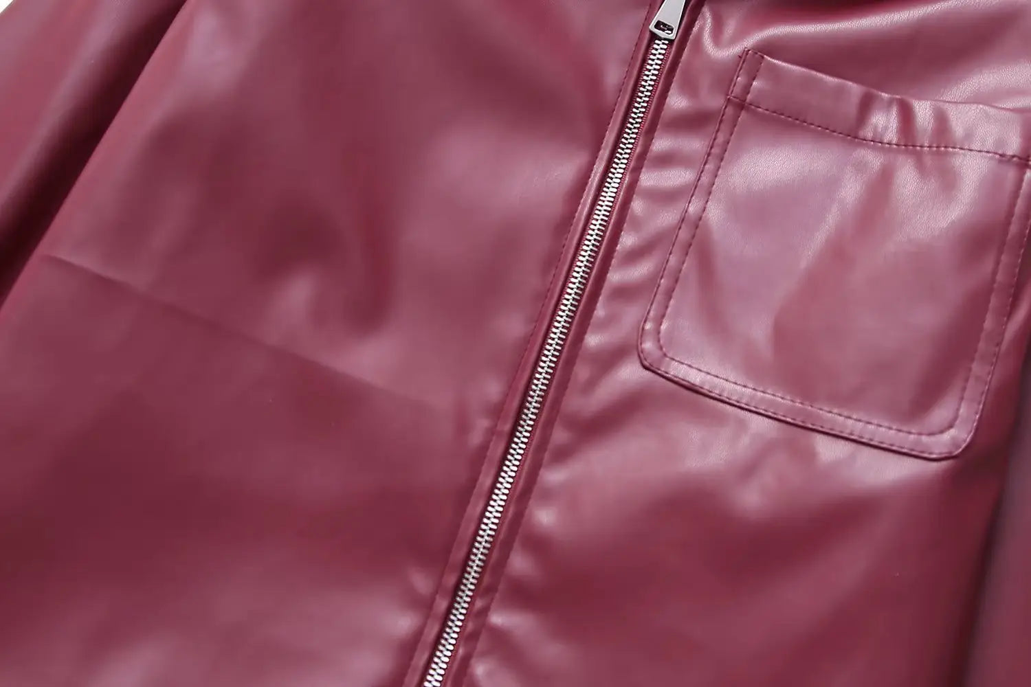 A sleek maroon faux leather biker jacket for women featuring a silver zipper and matching stitched pocket.