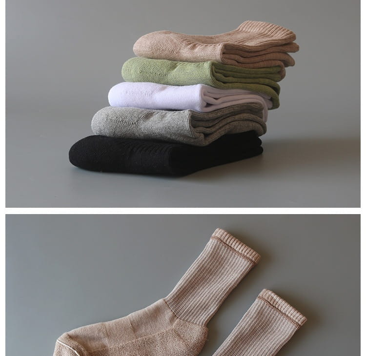 Pile de chaussettes de sport en coton épaissi, pliées soigneusement, dans des tons neutres, avec une texture côtelée et une matière en maille douce.