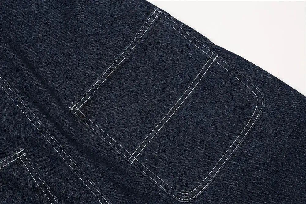 Dunkelblauer Jeanslatz-Taschenbereich mit kontrastierender weißer Ziersteppung an den Herren bestickten dunkelblauen Jeanslatzhosen.