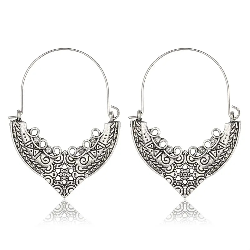 Silberfarbene Filigran-Mandala-Creolen im Crescent-Stil mit metallisch silberfarbenem Material und kunstvoll verzierter Ornamentik sowie kleinen klaren Edelsteinen entlang der geschwungenen Kante.