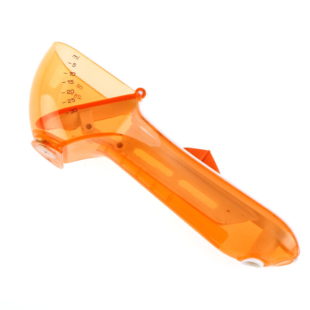Transparent orange plastic measuring cup with milliliter markings from adjustable measuring spoon set with magnetic base.