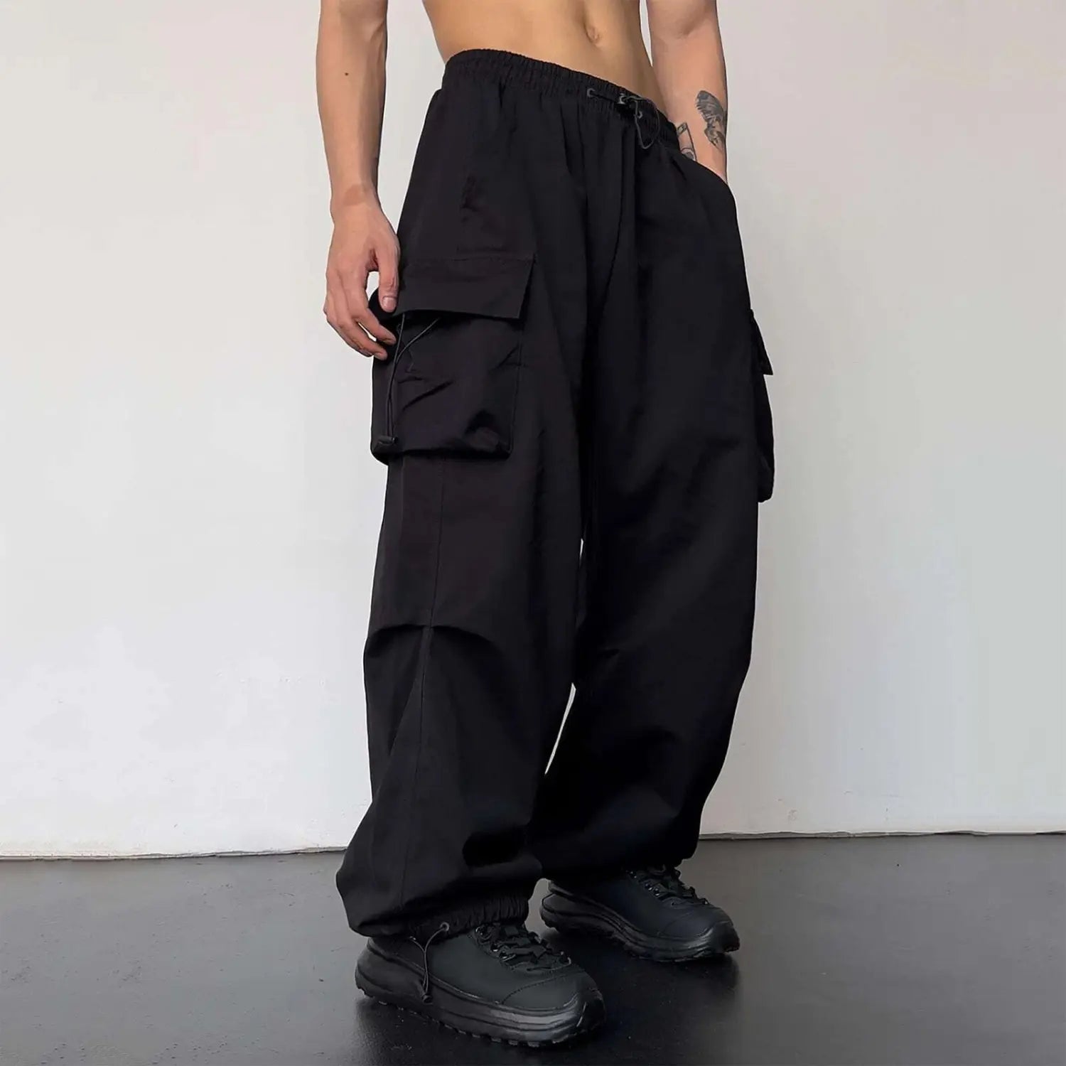 pantalon cargo noir à séchage rapide pour hommes, avec de nombreuses grandes poches, jambe ample et taille élastique à cordon de serrage, présenté sur le côté arrière.