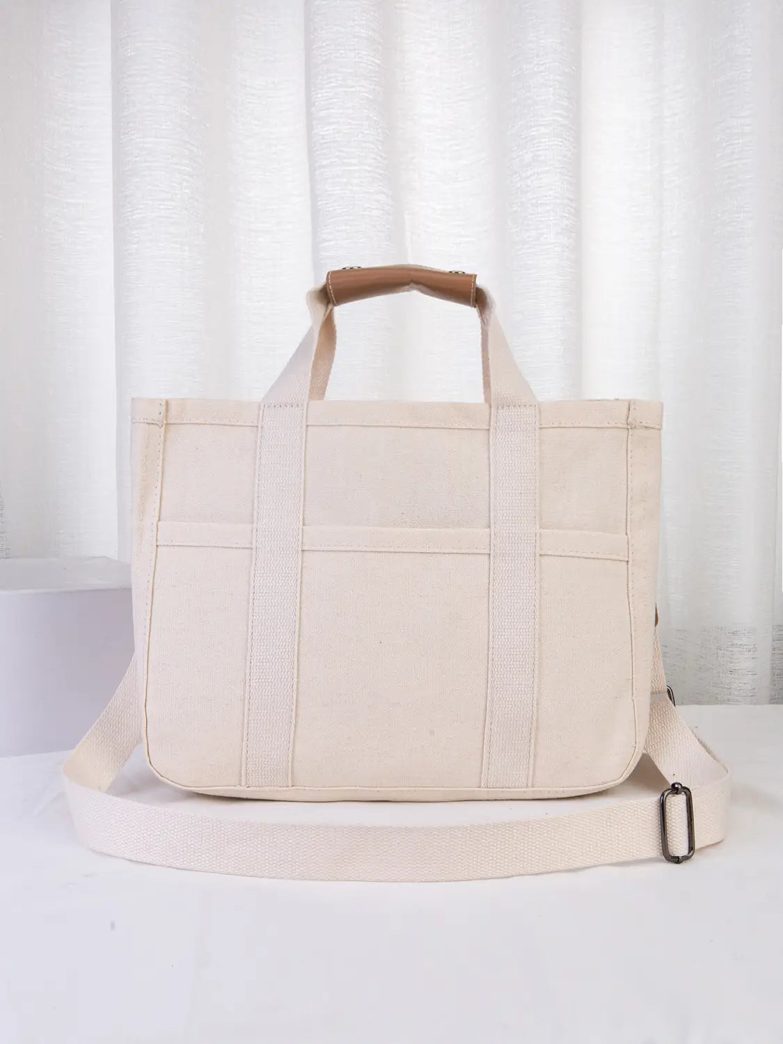 beige canvas messenger bag mother and baby travel tote with tan leather handles and a matching adjustable shoulder strap