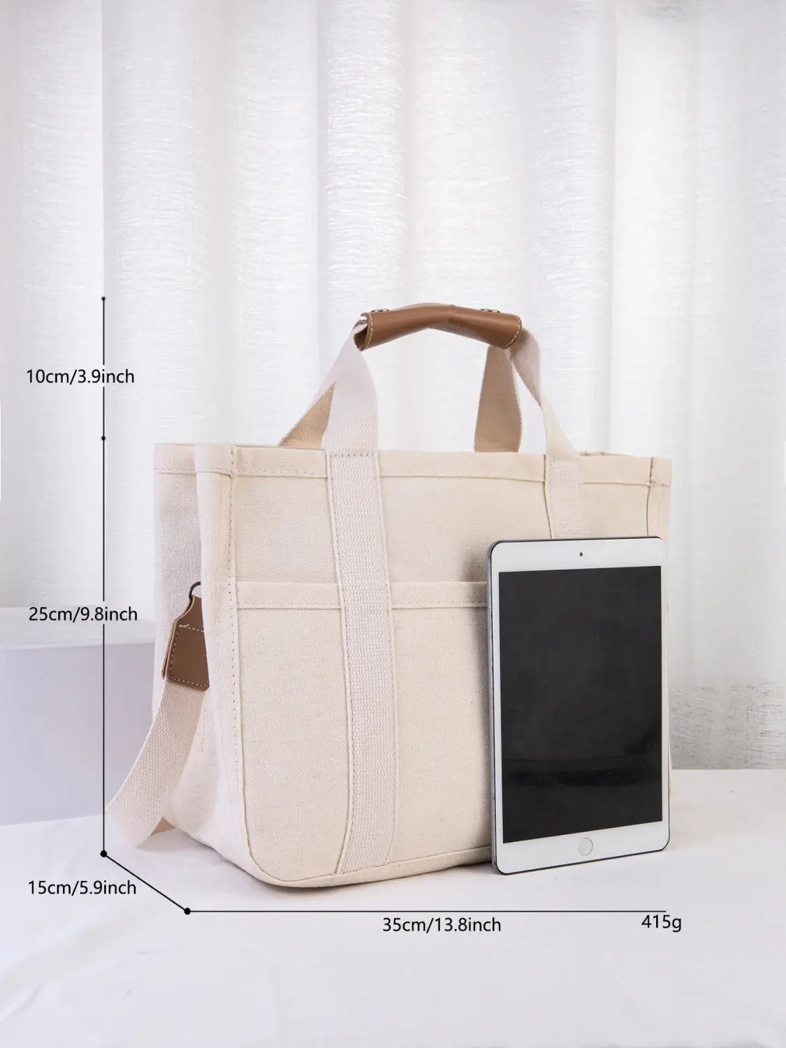 Beige canvas messenger bag with brown leather handles and matching shoulder strap designed as a mother and baby travel tote.