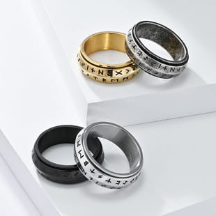 Three metallic spinner rings including a gold vintage caesar portrait stainless steel signet ring with engraved compass symbols and two silver-toned versions in black and brushed finishes.