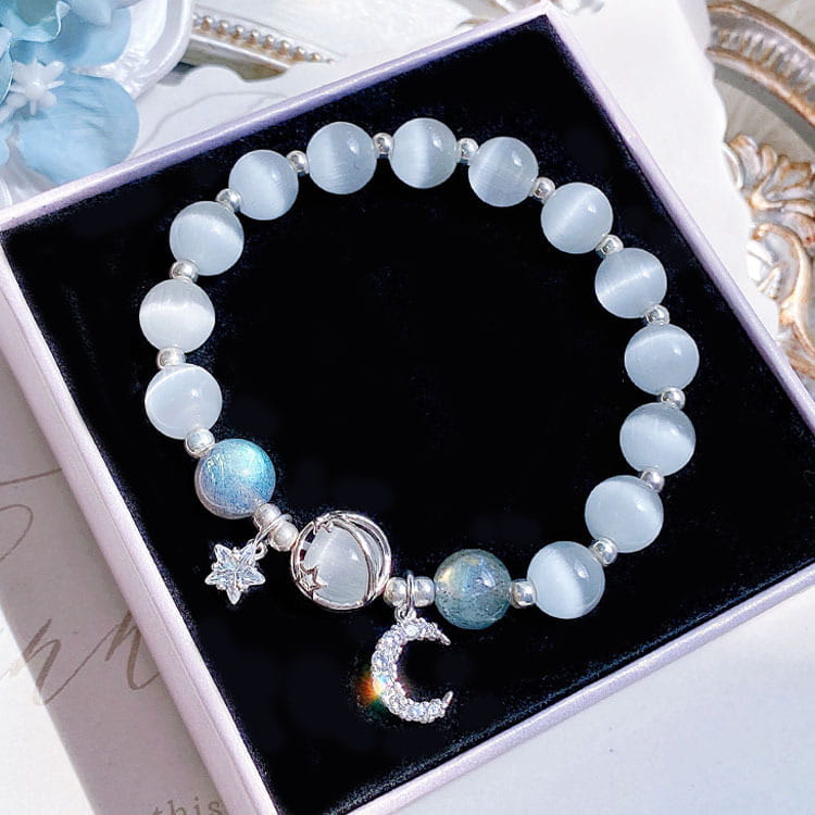 A handmade celestial moon and star crystal bead bracelet featuring light blue cat’s eye beads and silver-toned crescent moon charms with sparkling details.