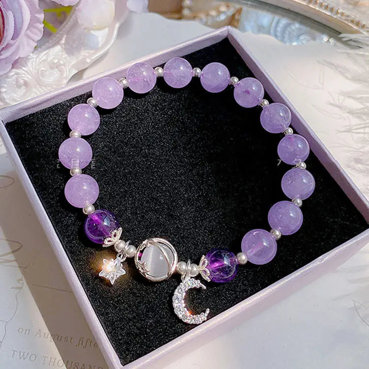 A delicate handmade celestial moon and star crystal bead bracelet featuring lavender crystals and silver charms.