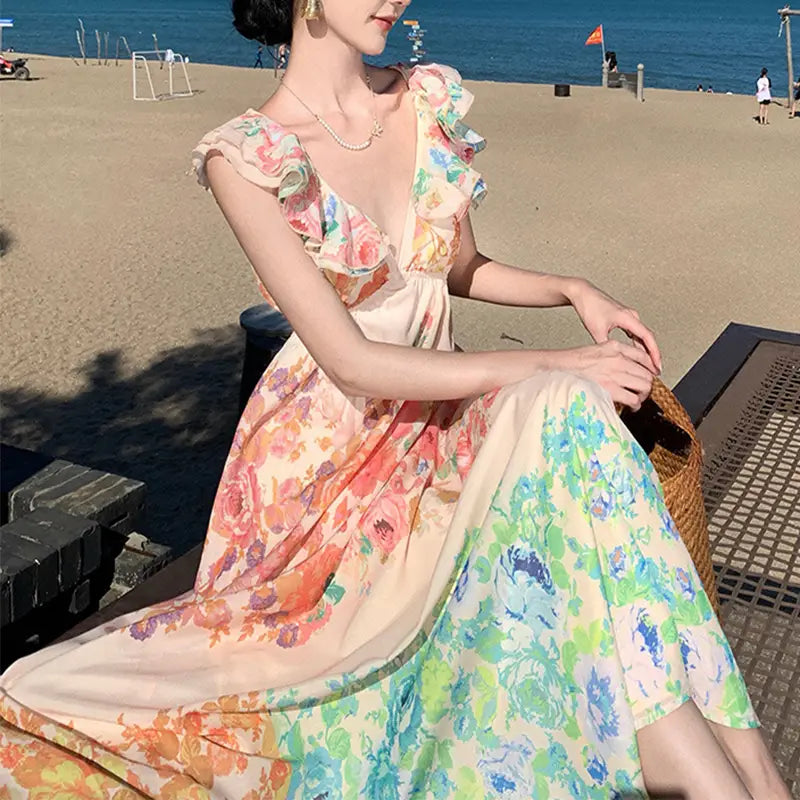 A flowing sleeveless French Floral v neck ruffle maxi dress in soft pastel tones of peach coral mint green and lavender featuring a v-neckline and ruffled shoulder straps.