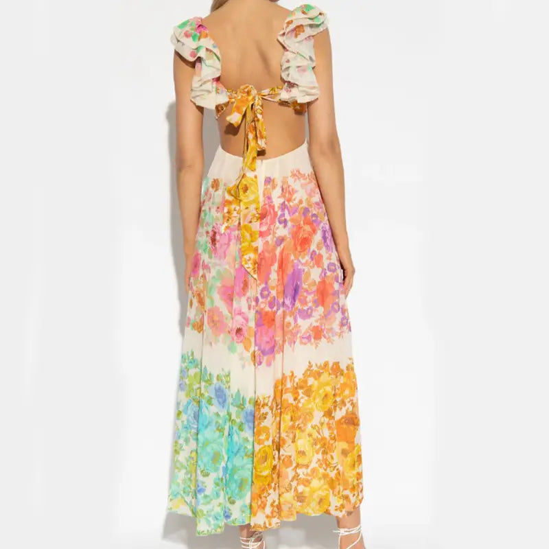 A vibrant backless french floral v neck ruffle maxi dress with ruffled shoulder straps and a tie-back detail shown from the back.