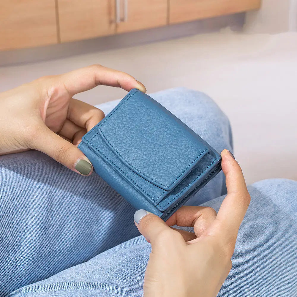 A compact bifold leather mini wallet made of textured blue cowhide with a flap closure and visible stitching.
