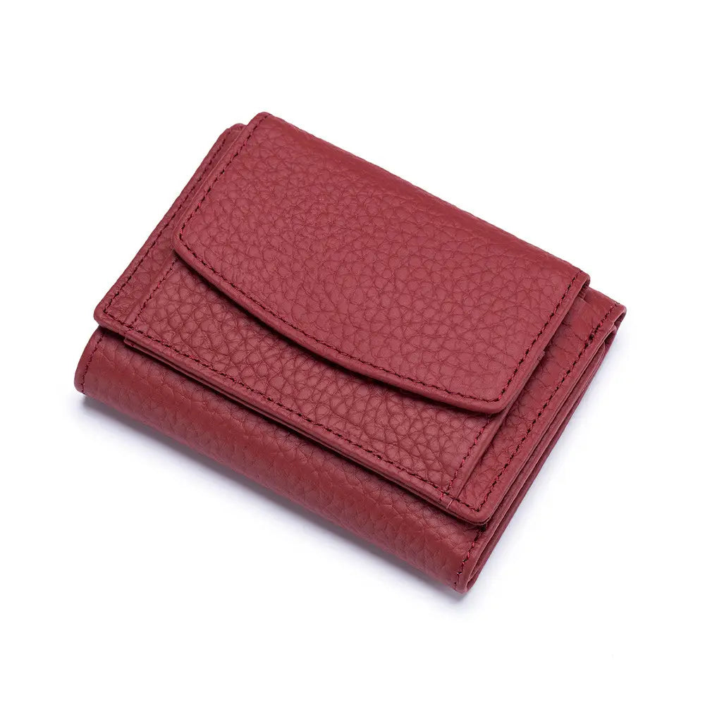 A compact red leather mini tri fold wallet made of textured cowhide with visible stitching along its edges designed as a bifold card holder.
