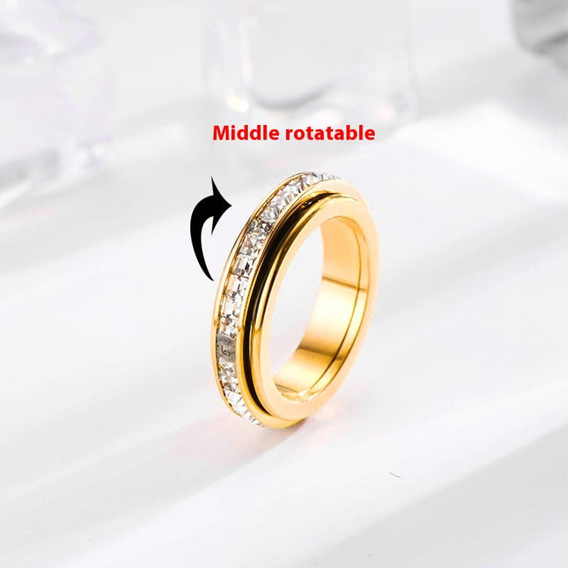 Rotating square diamond titanium steel ring in gold featuring a gold-toned spinner design with a central band embedded in clear crystals.