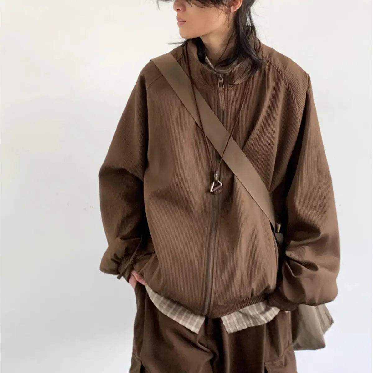Brown corduroy bomber jacket with zipper front and ribbed cuffs designed as retro loose outerwear.