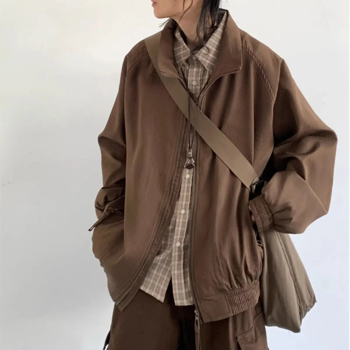 Brown corduroy bomber jacket with ribbed cuffs and hem featuring a retro loose fit and zipper closure.